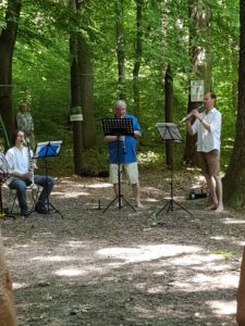 Auf dem Bild sind die drei Musiker des Klarinettenensembles der Musikschule Friedrichsdorf bei Spiel im Wald zu sehen.