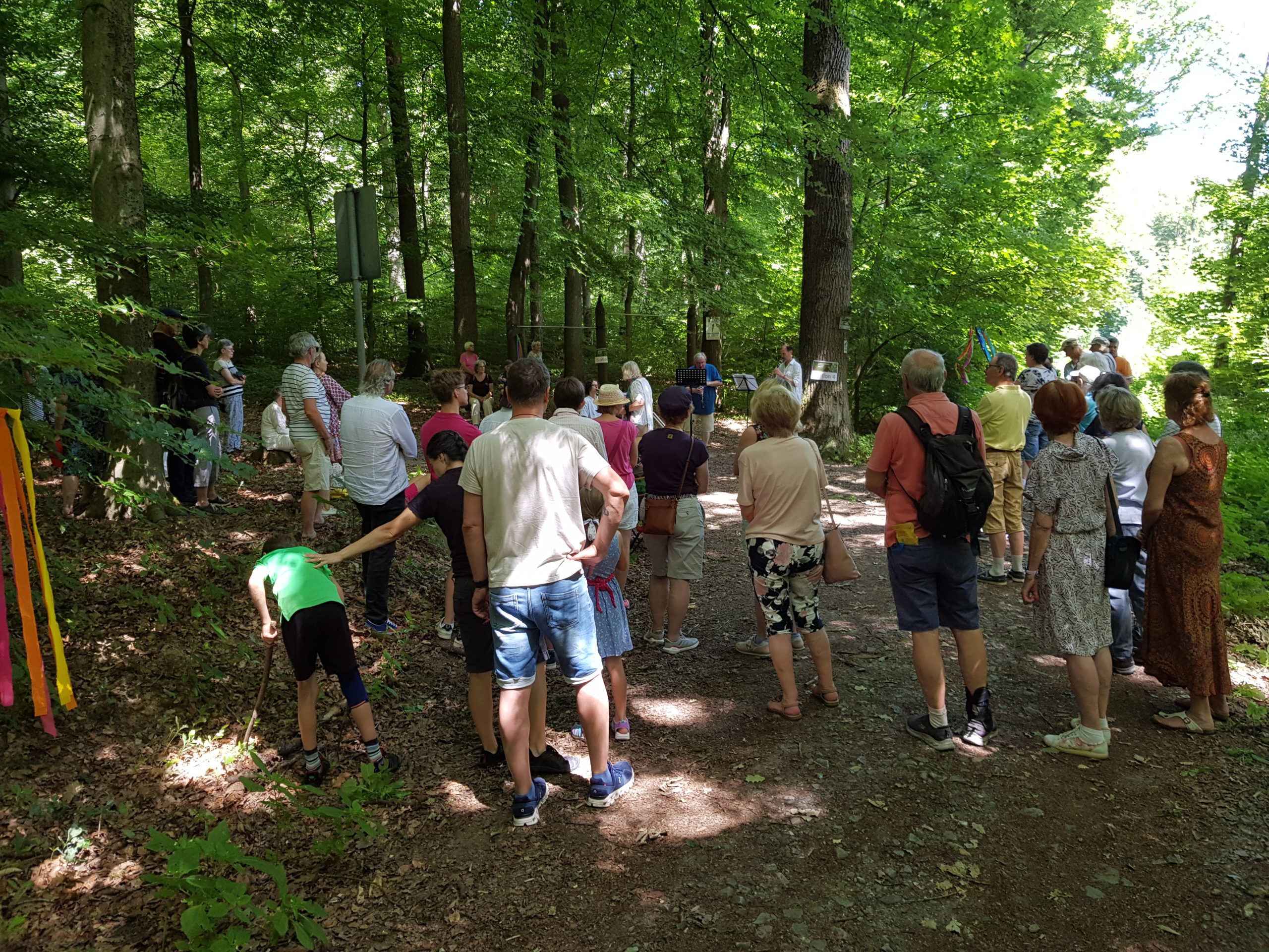 Besucher beim Wandelkonzert im Wald. Auf dem Bild ist eine Besuchergruppe zu sehen, die dem Wandelkonzert im Wald lauscht.